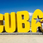 Bella standing in front of large yellow Cuba sign