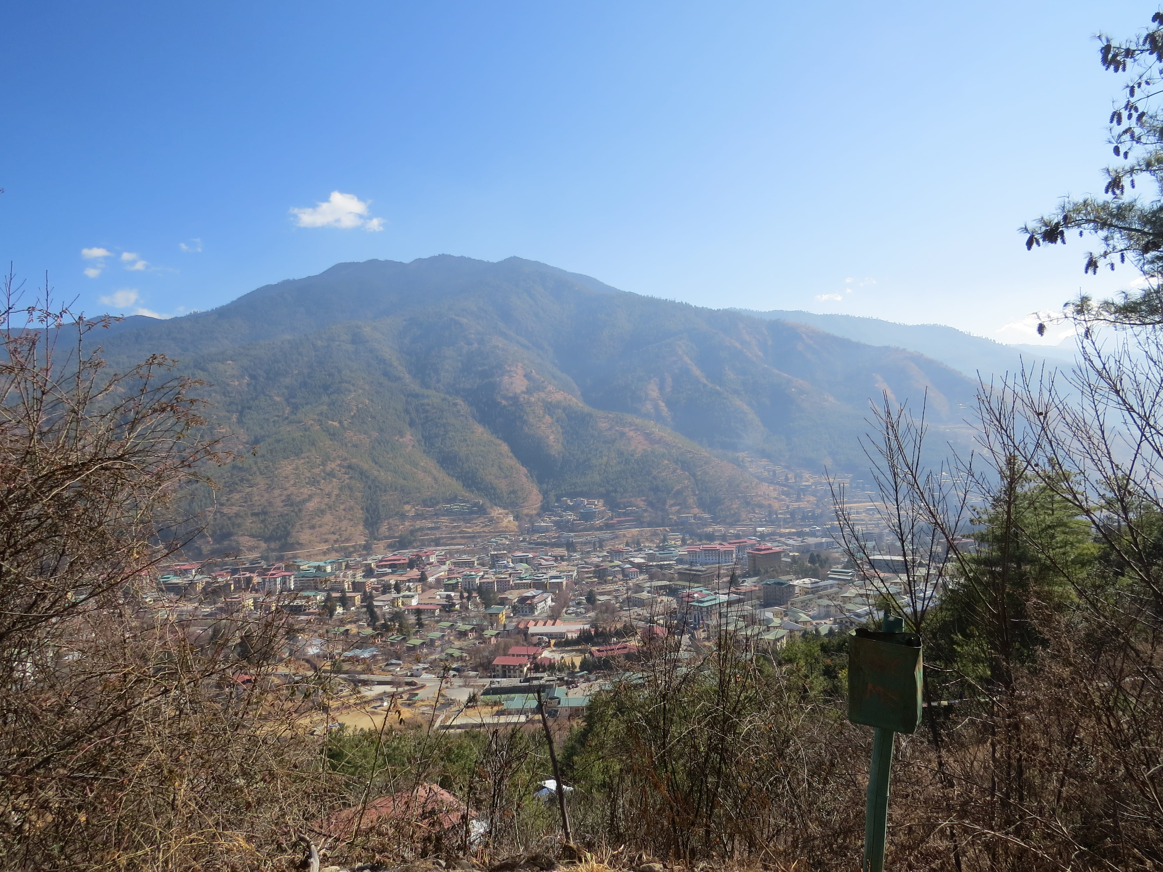 View of Thimphu, Bhutan's capital, from above with mountains and blue sky in background