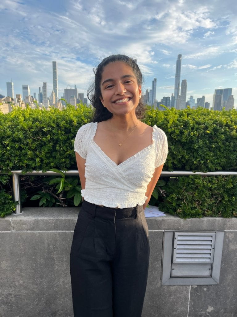 Jackeline smiles and poses in front of a city skyline