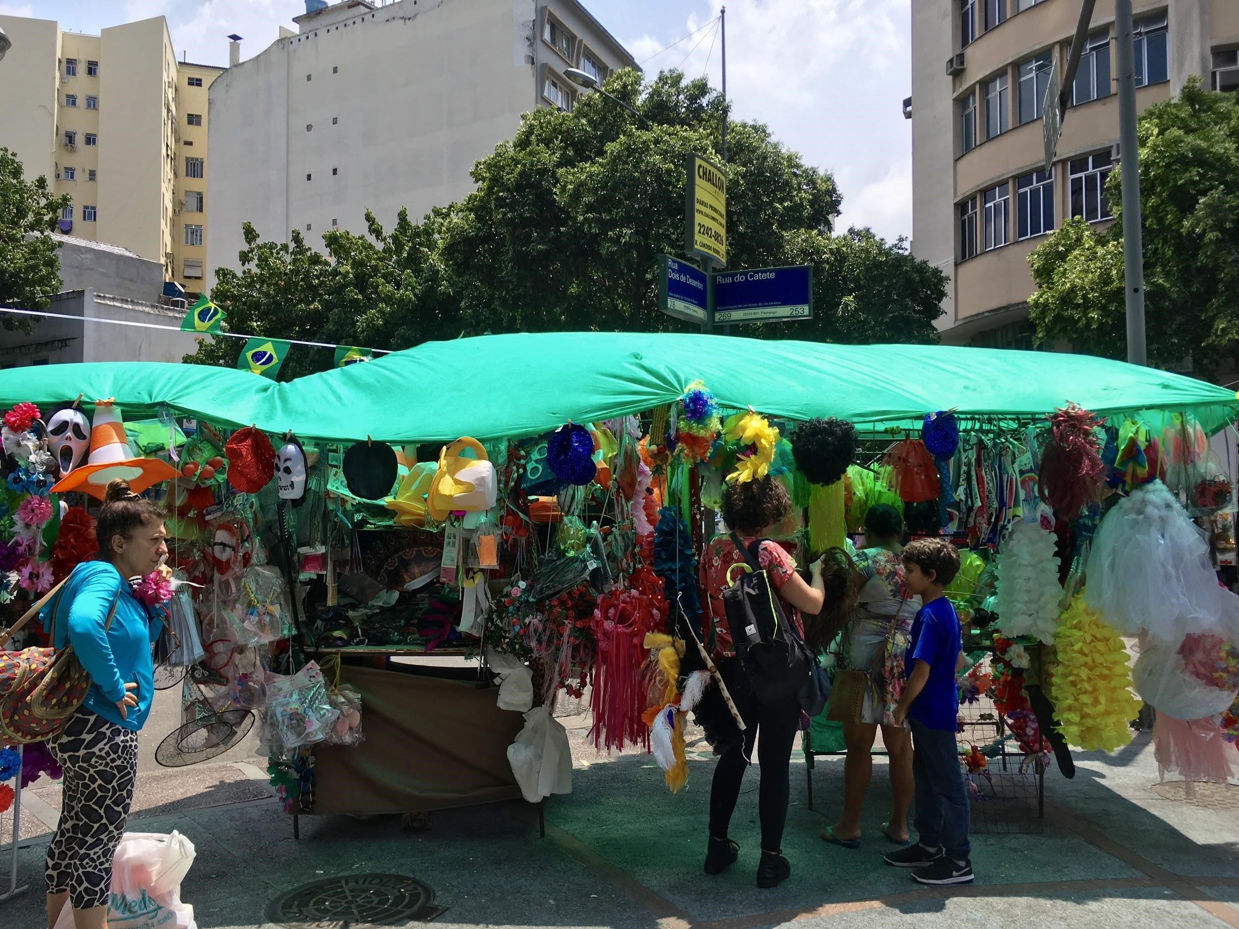 Street vendors selling costume items, such as colorful tutus, pirate hats, and bunny ears