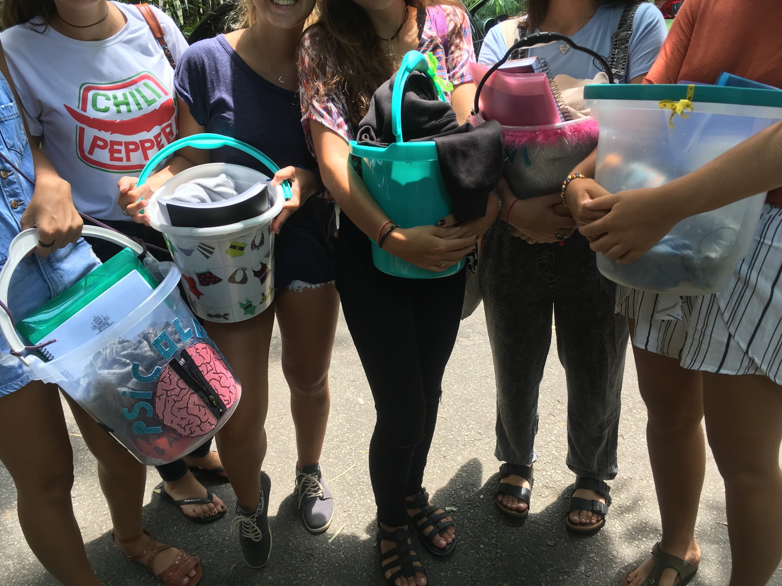 Group of Brazilian university students holding buckets they're using instead of backpacks during first weeks of school