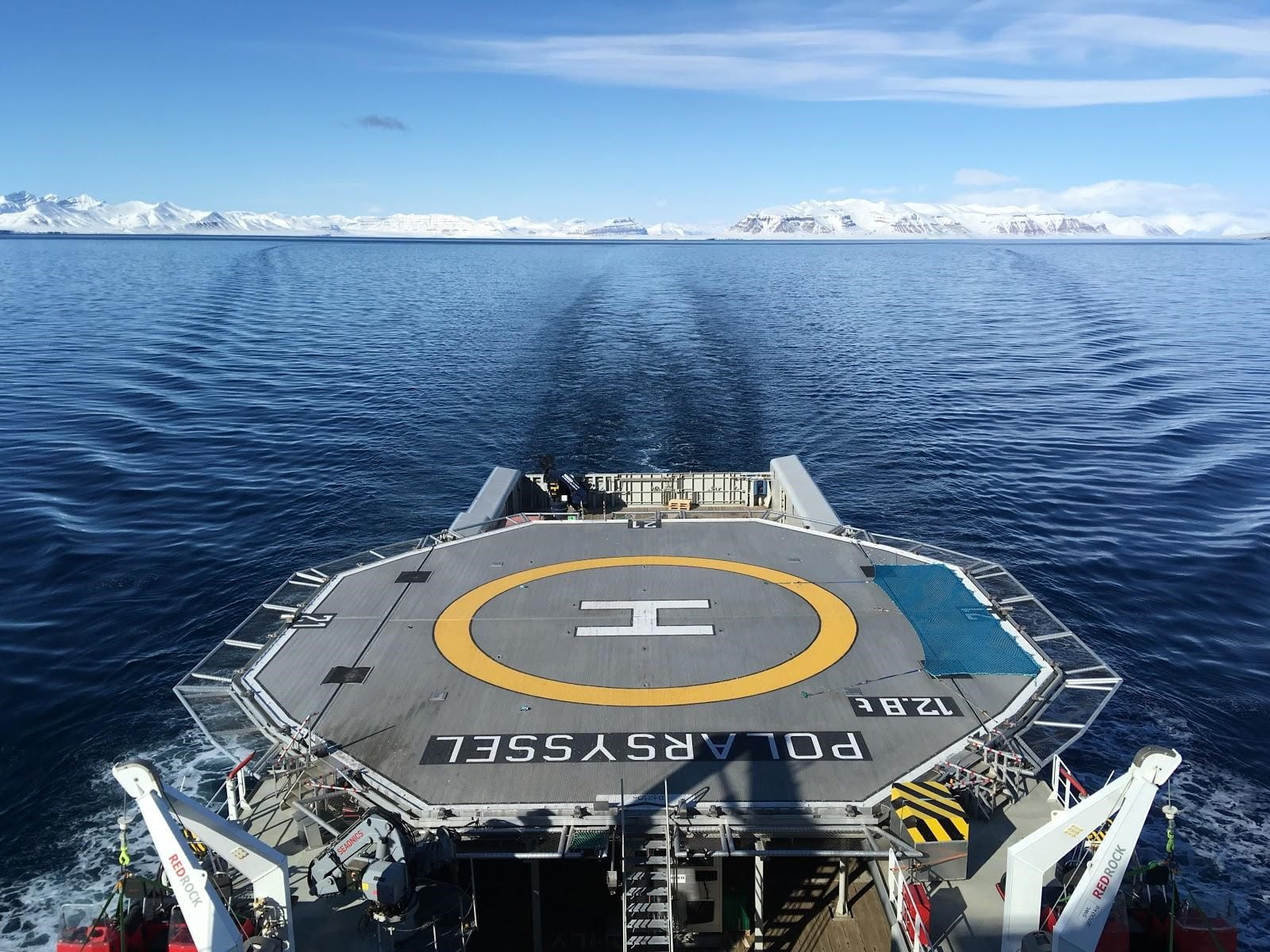 Large flat, government boat with letter H in yellow circle in Arctic waters