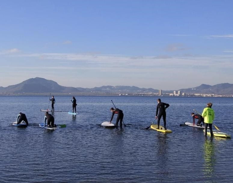 Stuart and seven others in water on paddle boards, mountains in the background.