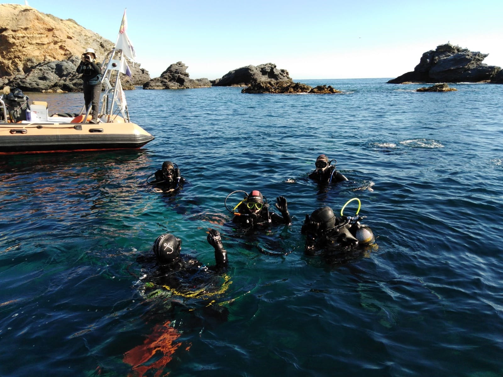 Five students wearing scuba gear float atop greenish-blue water