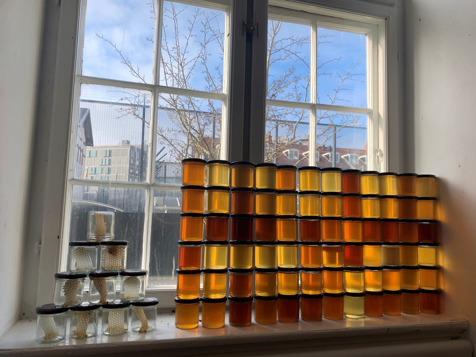 Jars of honey stacked on a windowsill