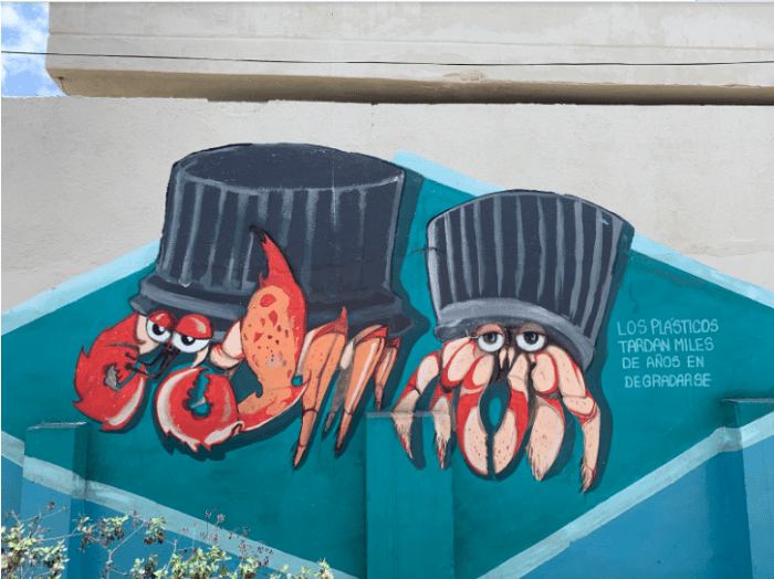 This mural depicts crabs with to-go containers in the place of their shells. The caption says, “plastics take thousands of years to degrade.”