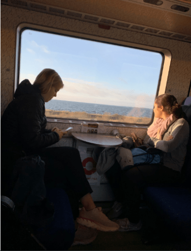 Two girls looking out the window of a train